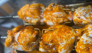 Whole chickens roasting on a Cyprus foukou charcoal rotisserie grill with stainless steel skewers, perfect for Greek souvla and kontosouvli style BBQ queens ny